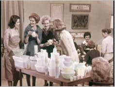 Women gather around a table with Tupperware products
