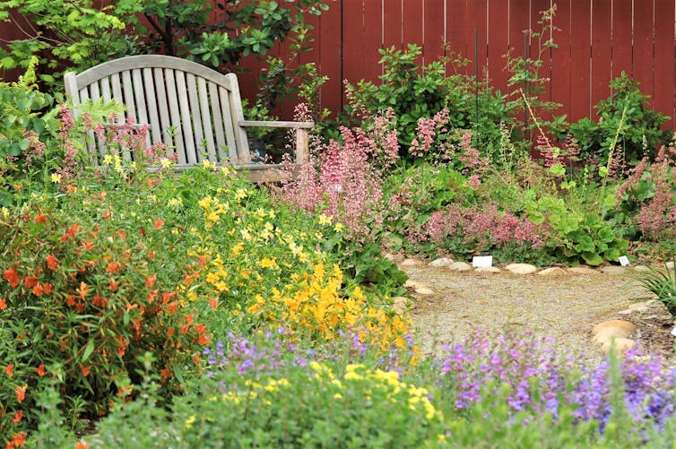 A garden with wildflowers in several areas and a bench.