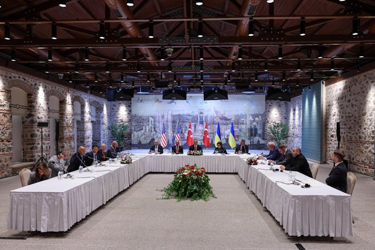 A group of people are seen sitting around a large table.